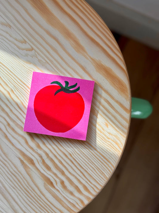 Pink post-it note pad with a red tomato illustration on it 