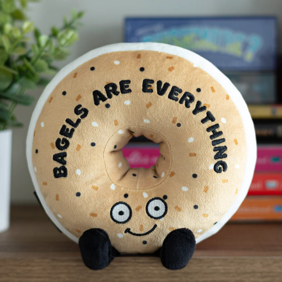 Bagel plushie sitting on a bookshelf
