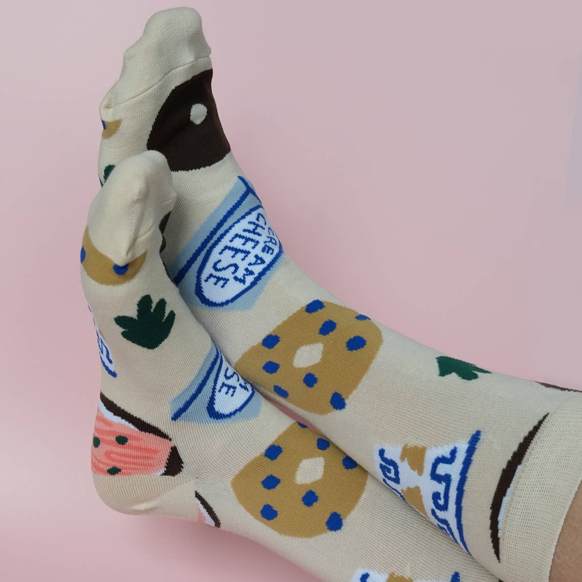 Bagel socks on models feet -- design features bagels, coffee cup, cream cheese and lox