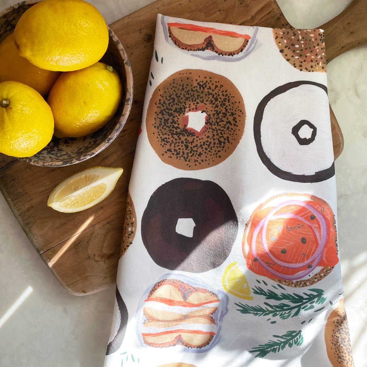 Bagel tea towel on cutting board next to a bowl of lemons