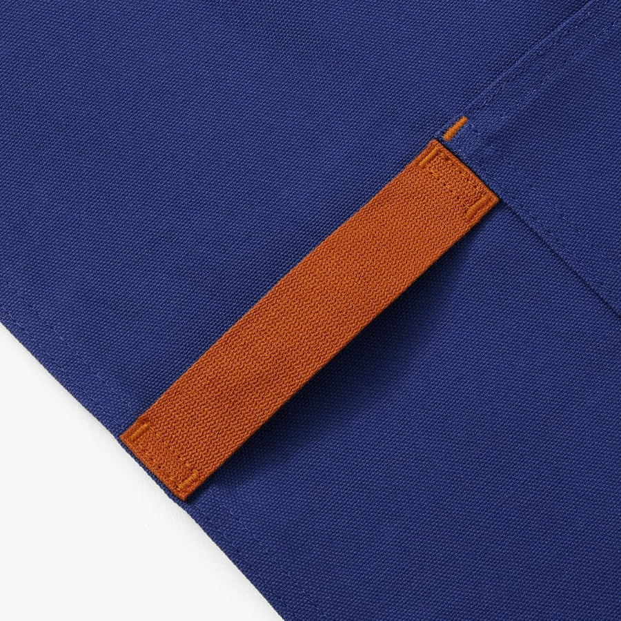 Blue apron with navy/black straps. This apron highlights 4 different styles of bagels. This photo shows the detail of the towel strap.