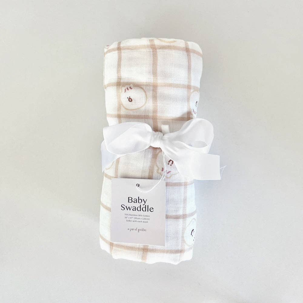 Plaid baby swaddle with a white bow on a light gray background