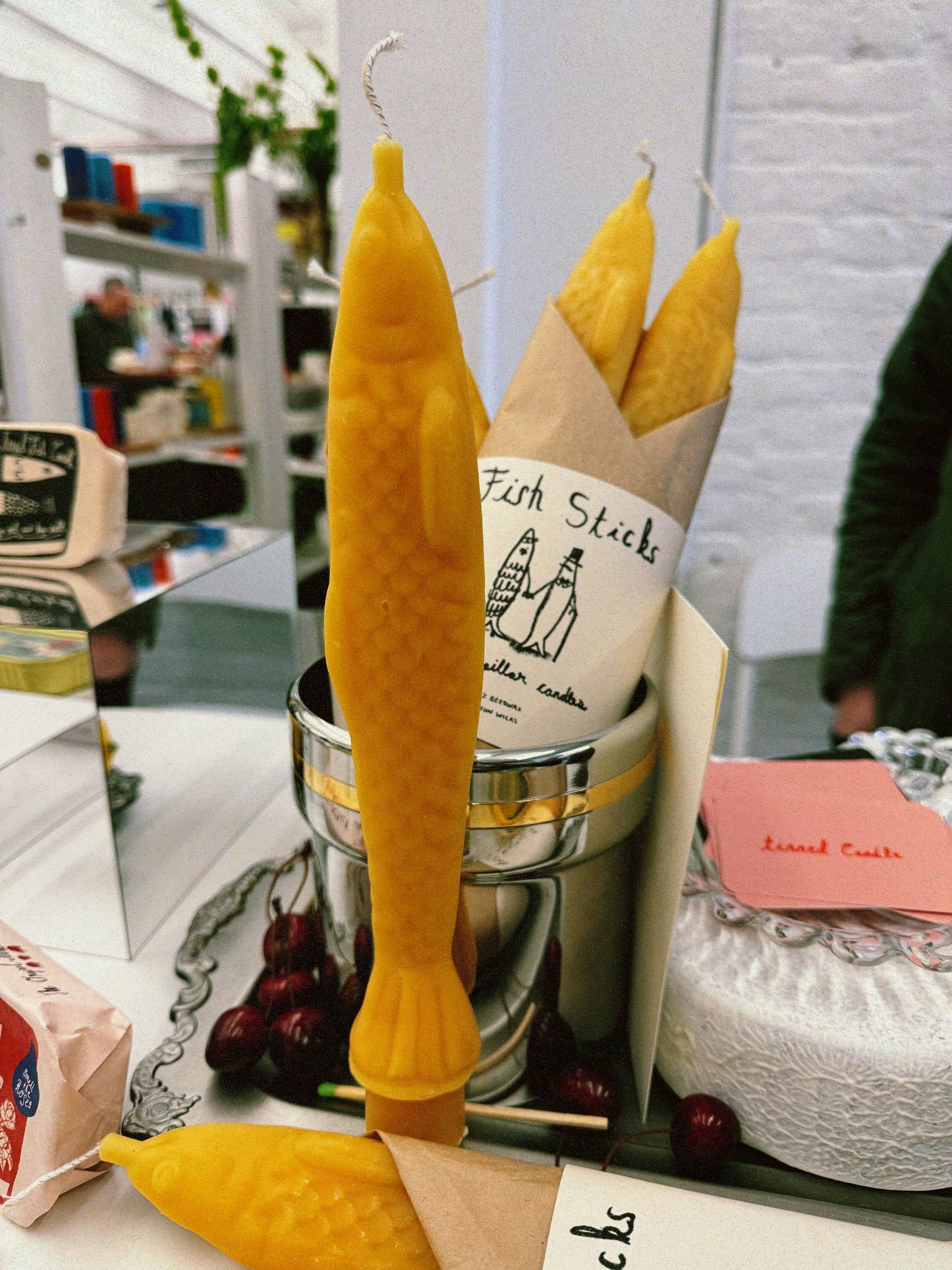 Single yellow beeswax taper candle shaped like a fish. Shown unwrapped on countertop.