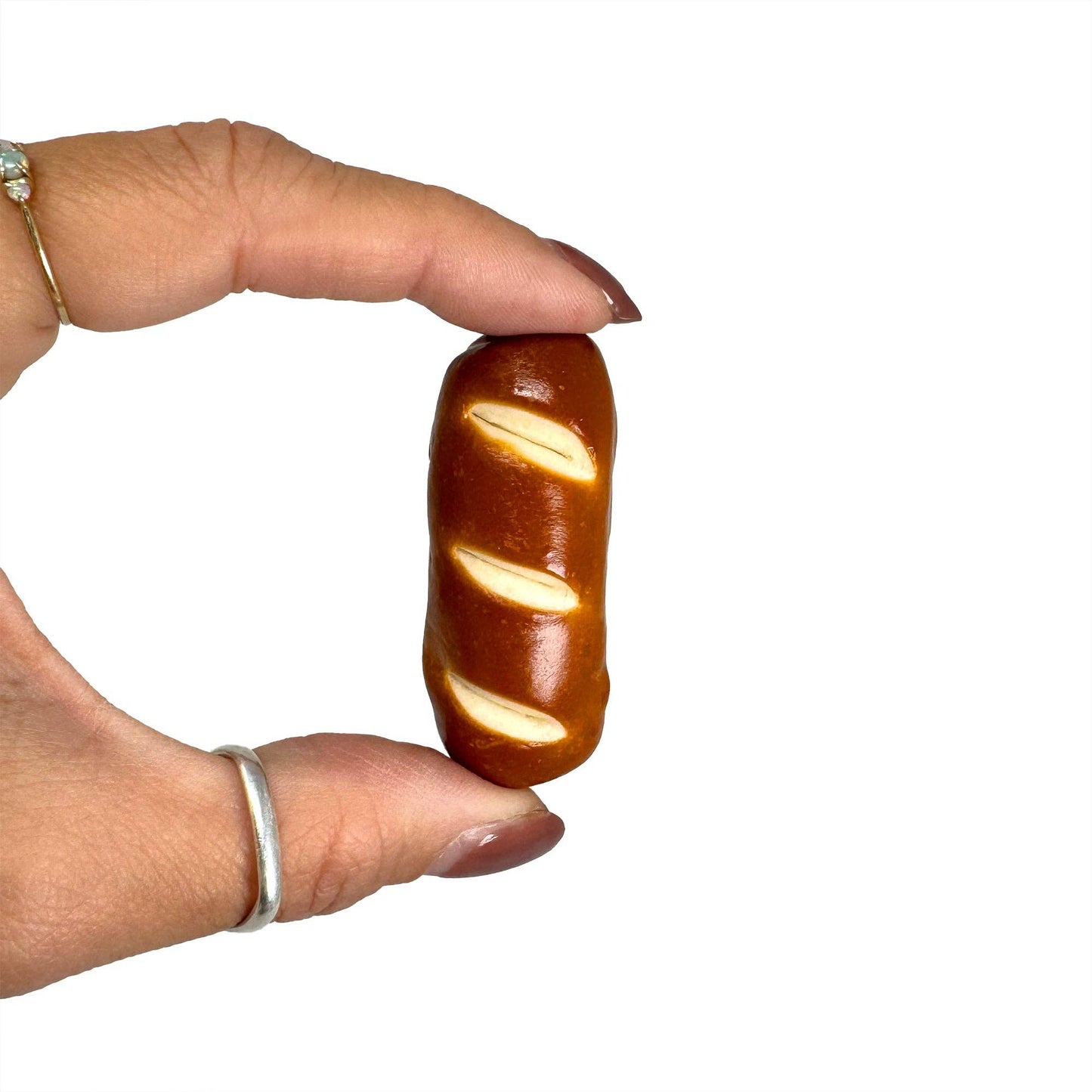 Keychain shaped like a realistic baguette (or pretzel roll) with toasty brown crust scored diagonally three times.