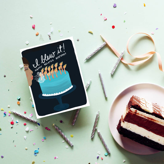 belated birthday greeting card displayed with confetti, candles, ribbon and a slice of cake.