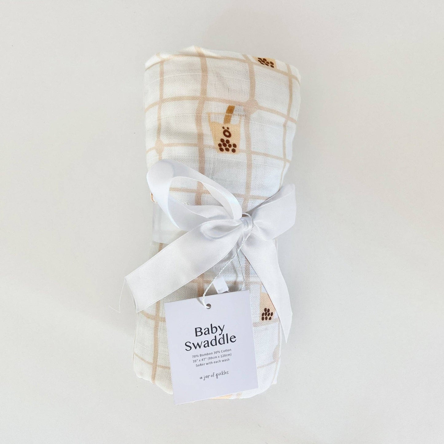 Baby swaddle with plaid pattern and white ribbon on a light gray background