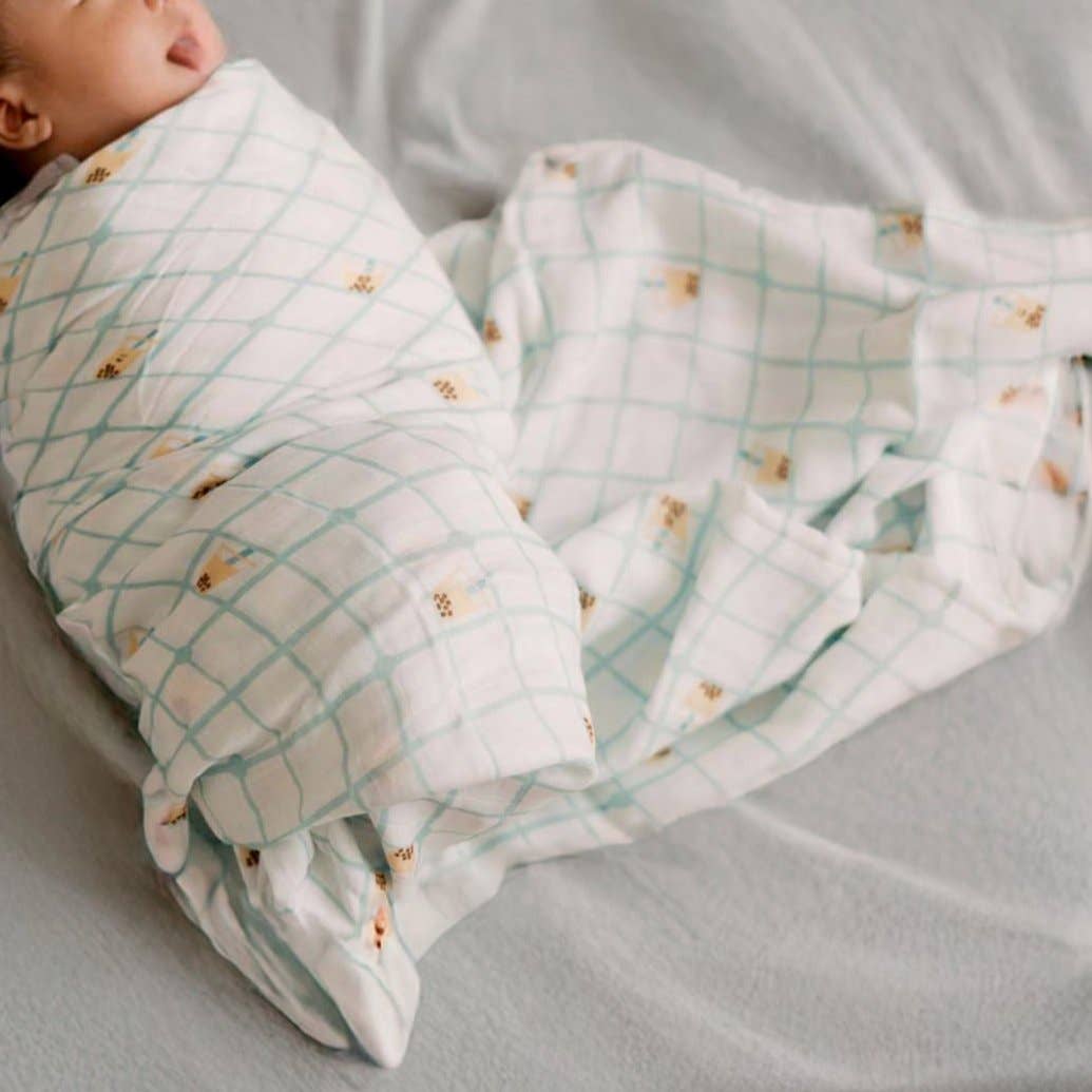 Newborn baby swaddled in a soft blanket with a grid pattern on a neutral background