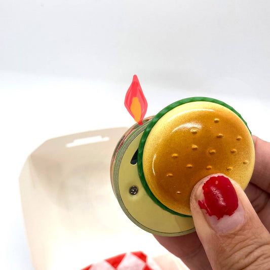 Butane lighter shaped like a hamburger. Shown held in a person's hand for size reference.