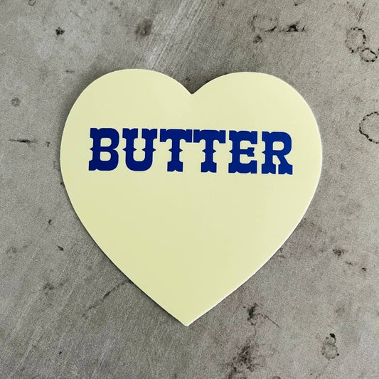 Heart shaped sticker with blue text in center that reads "butter"