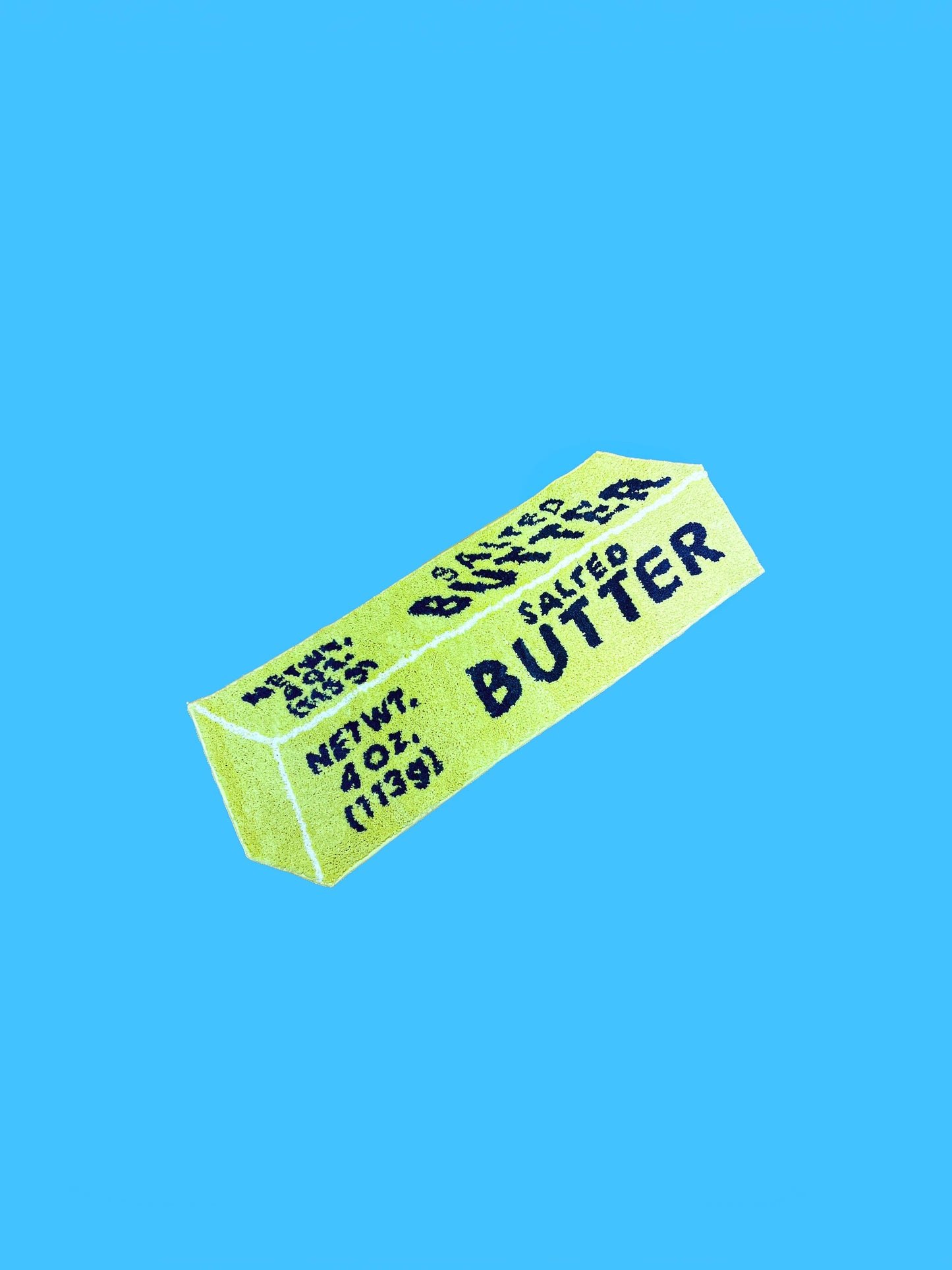 Rug made to look like a stick of salted butter on blue background