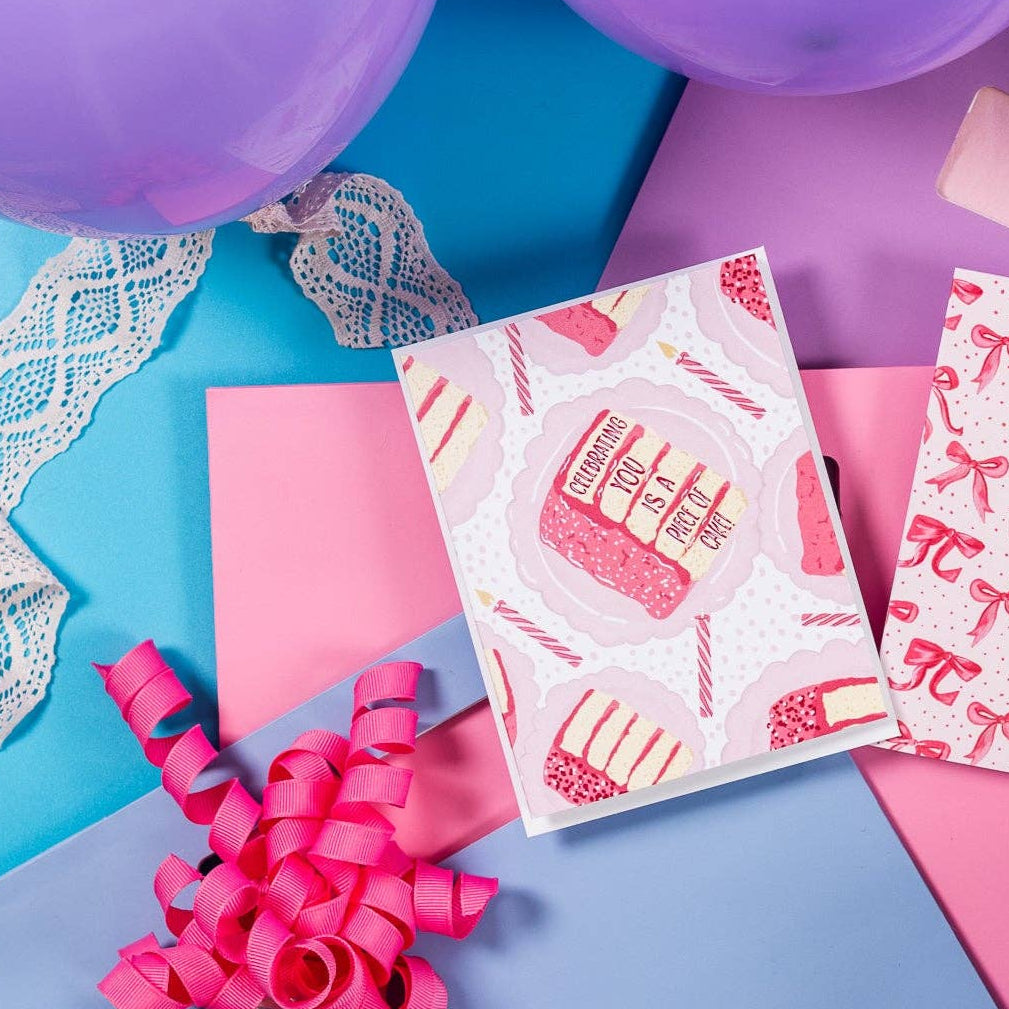 Celebrating You Is A Piece Of Cake Birthday Card shown with pink ribbons and purple balloons on a colorful background.