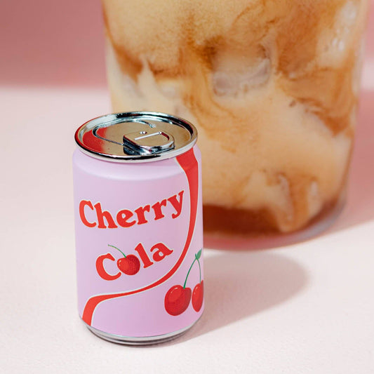 Refillable lighter shaped like a "Cherry Cola" soda can - white with red stripe and pair of cherries on the side. Shown next to a bubbly soda in a glass.