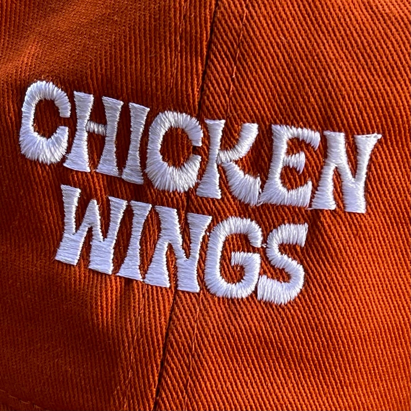 Buffalo sauce colored dad hat with text that reads: Chicken Wings