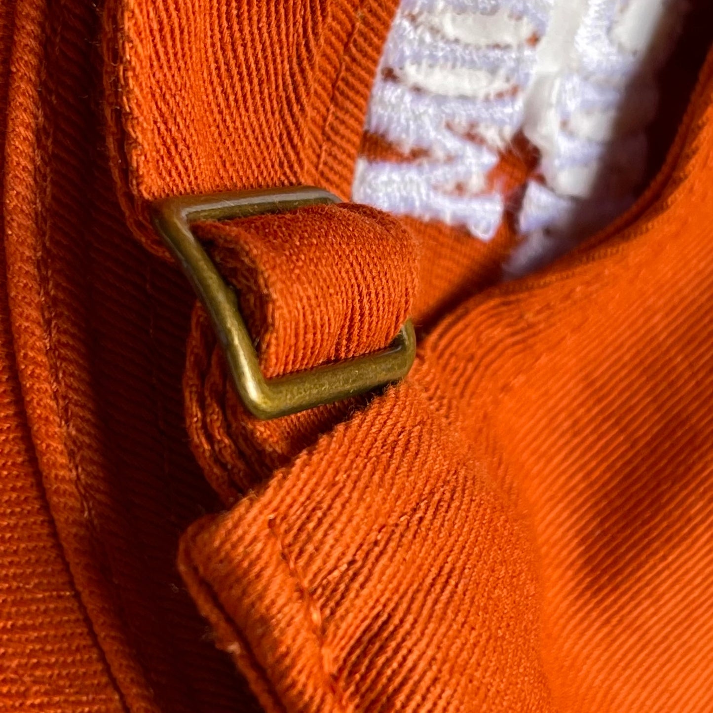 Buffalo sauce colored dad hat with text that reads: Chicken Wings. Photo is showing the back clasp of the hat that makes it adjustable.