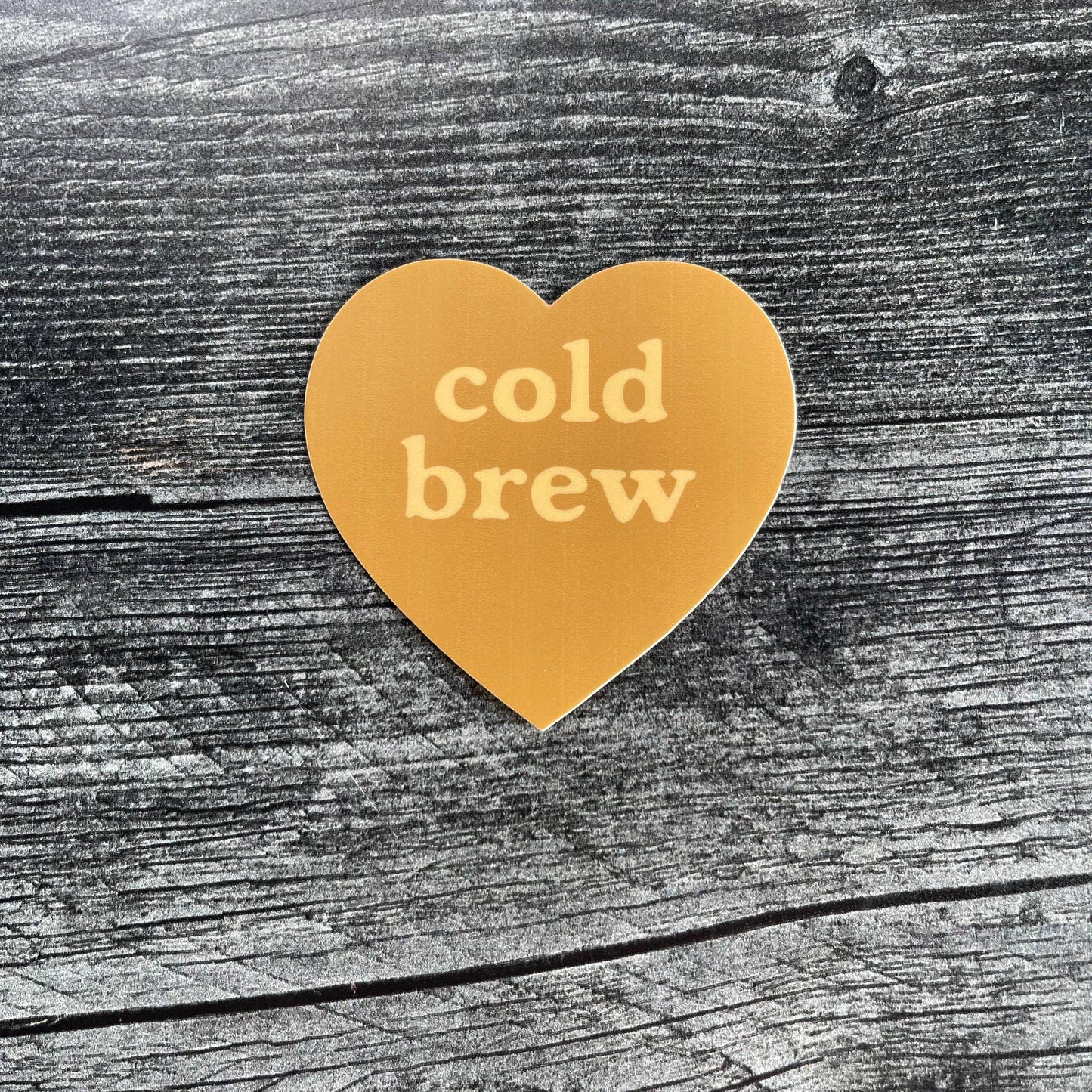 Heart-shaped 'cold brew' sticker on a wooden surface