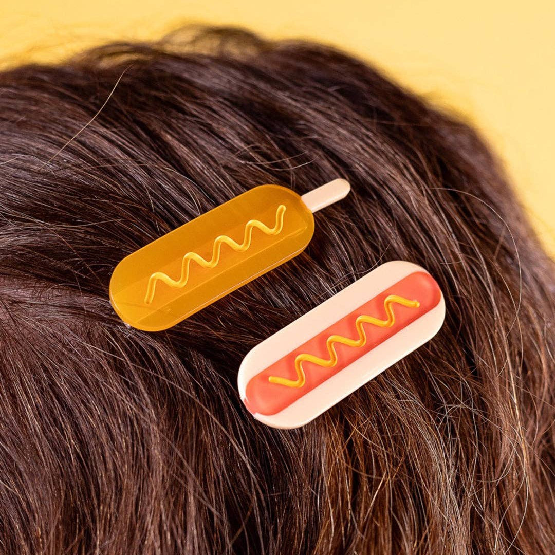 Corndog hair clip and hotdog hair clip being worn on brown hair.