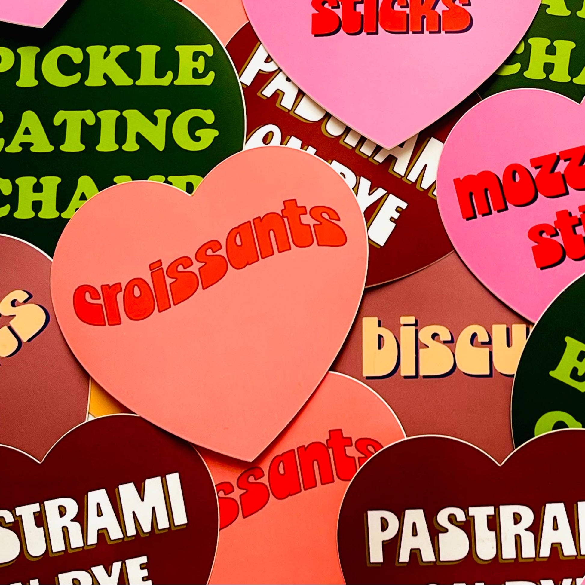 Heart-shaped stickers with various food-related text on a colorful background