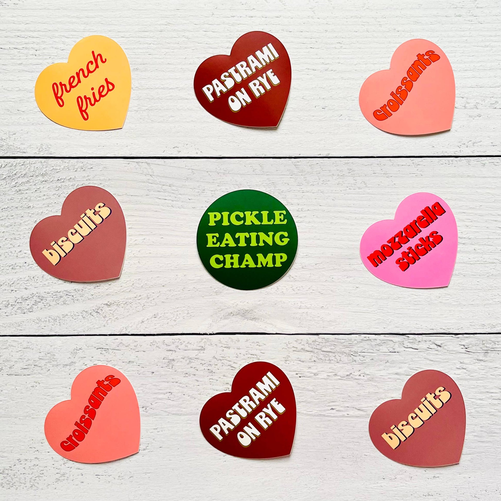 Heart-shaped stickers with various text on a wooden surface