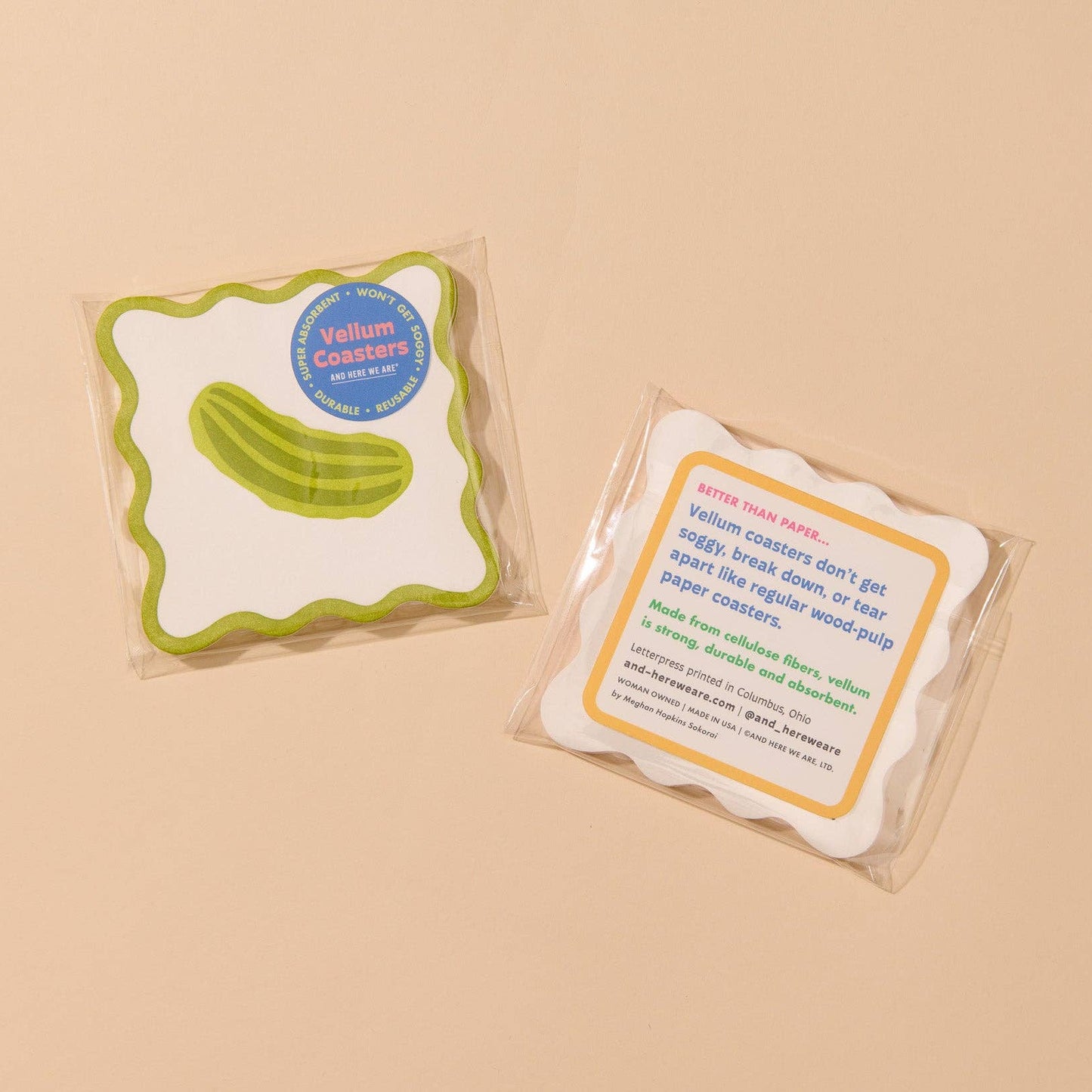 Two packaged Vellum Coasters on a warm beige background. One coaster is lime green and white with a cucumber graphic, and the other is white with a yellow border and product text.
