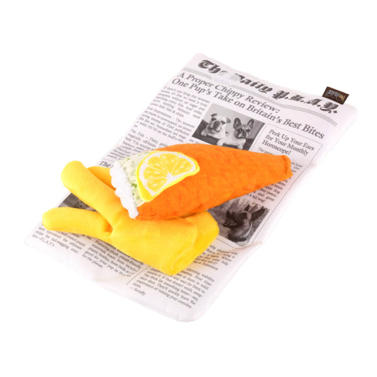 Dog toy shaped like a fried fish with a lemon on top, placed on a newspaper background.