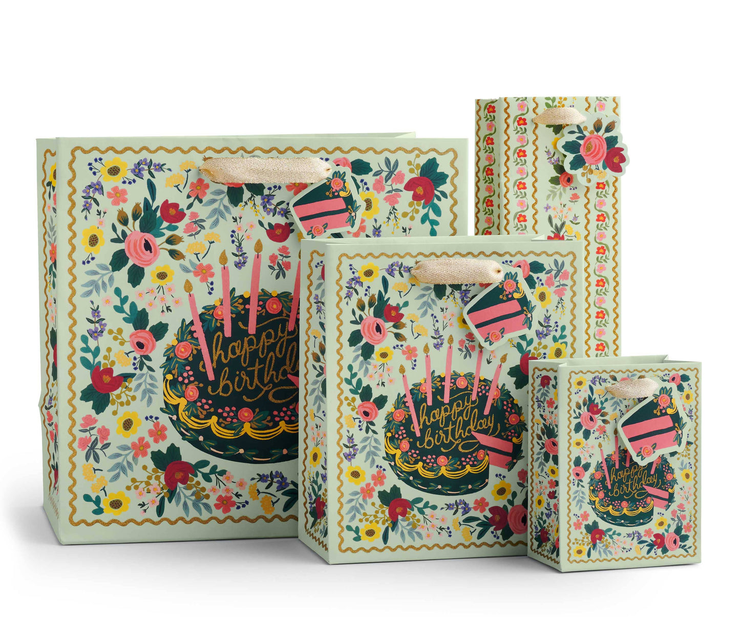 Gift bag shown in assorted sizes. Image on white background - intricate, vintage-inspired floral print surrounding birthday cake decorated with pink and purple flowers, dark frosting base, and pink candles. Squiggly golden yellow border. Very maximalist.