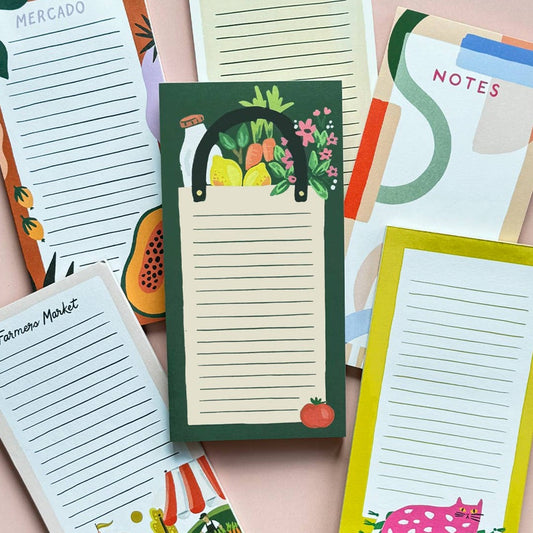 Several notepad scattered on a table to have a focus on the center notepad which is a grocery bag notepad