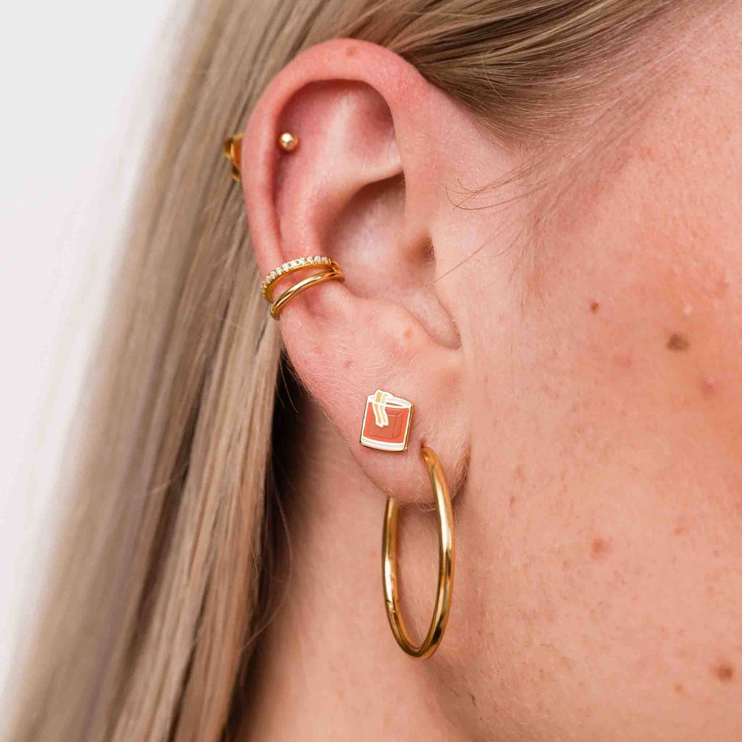 Various earrings on ear lobe. Being showcased here is the single old fashioned stud earring