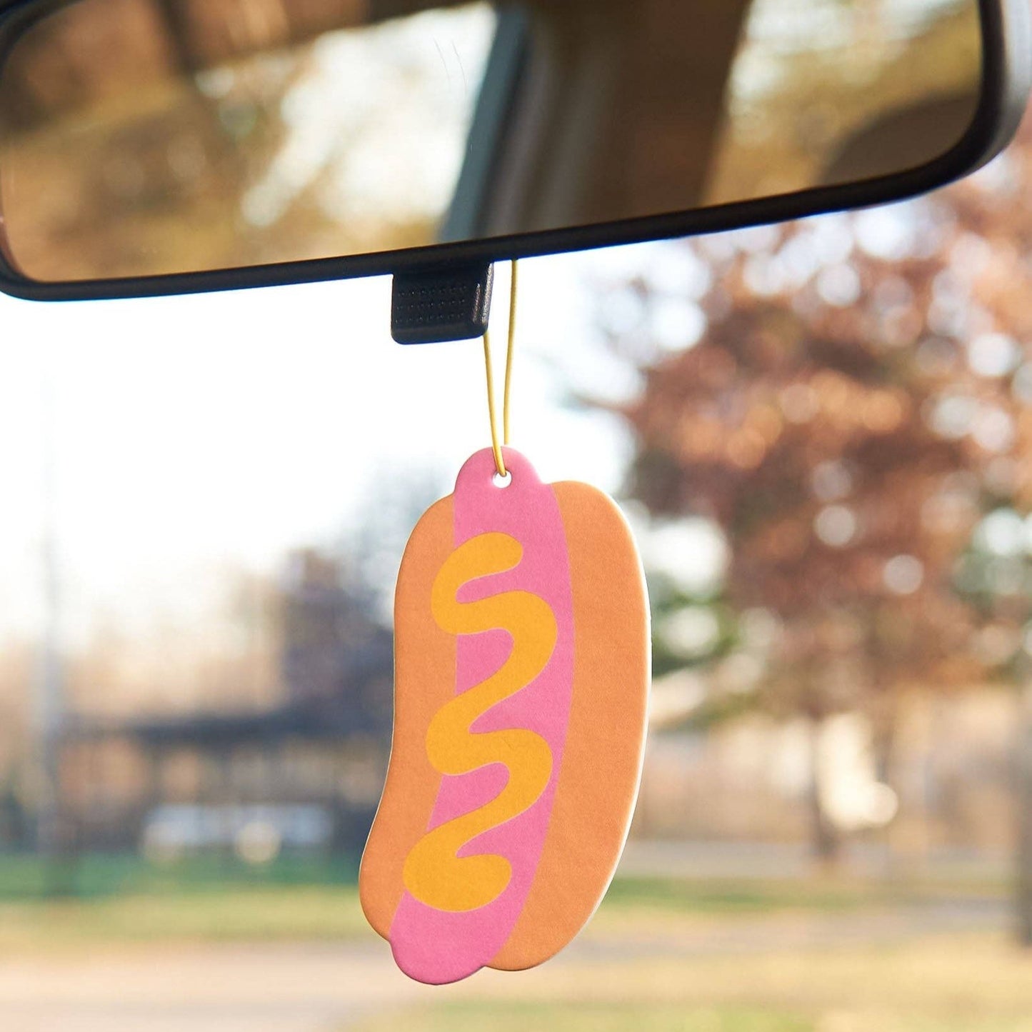 Hot dog shaped air freshener hanging from rear view mirror