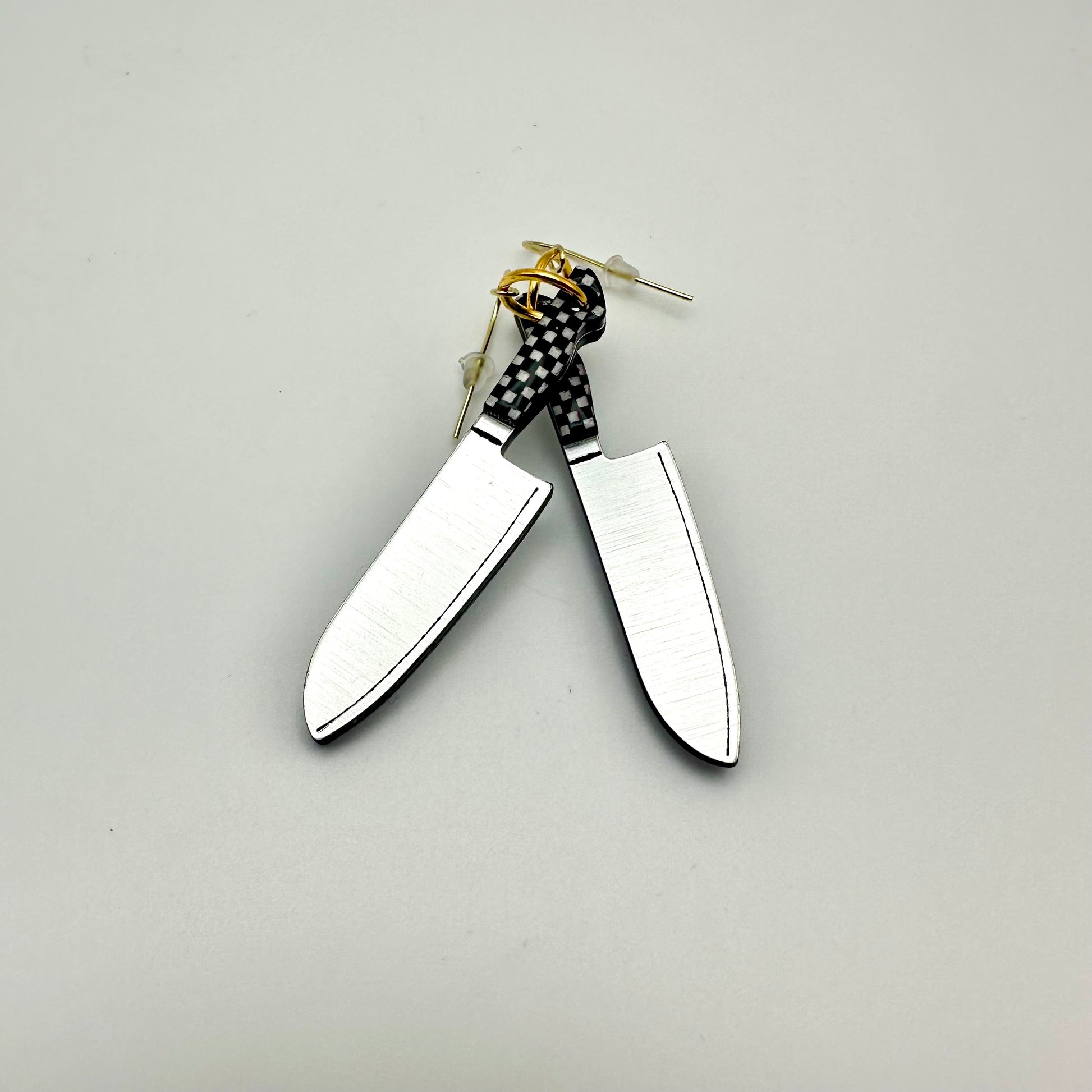 2 earrings that look like knives. The handles are black and white checker. 