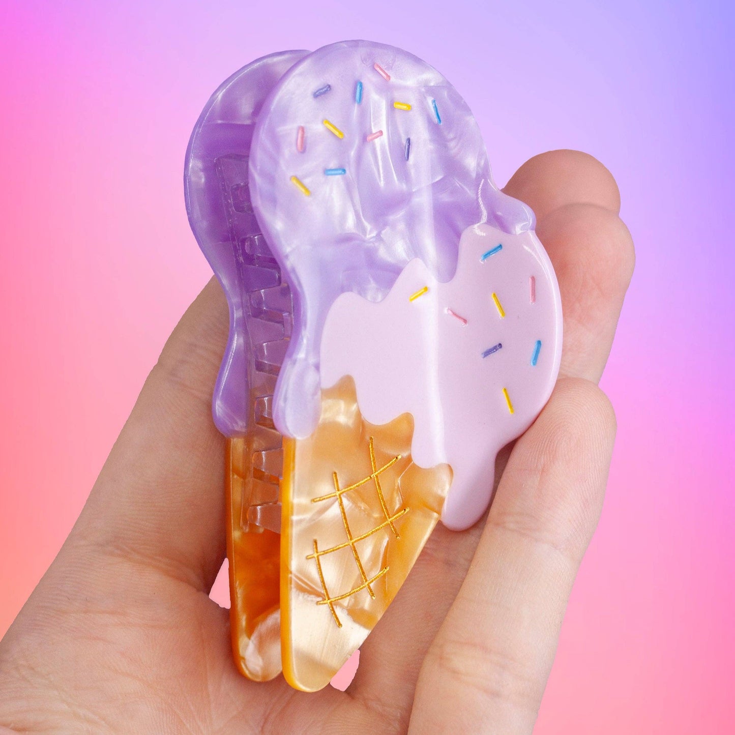 Hair claw made to look like two scoops of ice cream (one pink, one purple) melting on a waffle cone