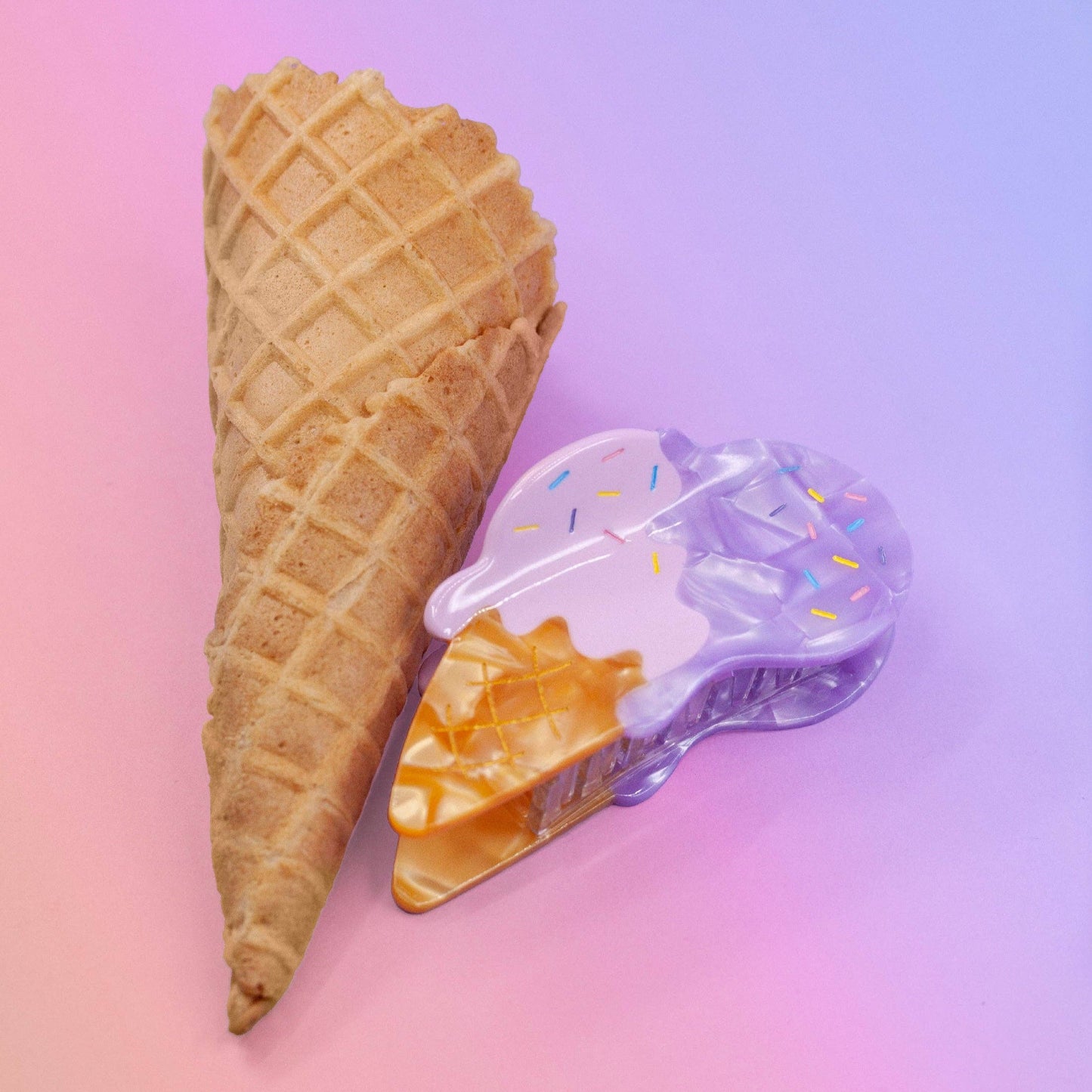 Hair claw made to look like two scoops of ice cream (one pink, one purple) melting on a waffle cone. Pictured here next to an actual waffle cone
