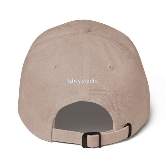 Beige cap with 'kirty studio' embroidered on the back against a white background