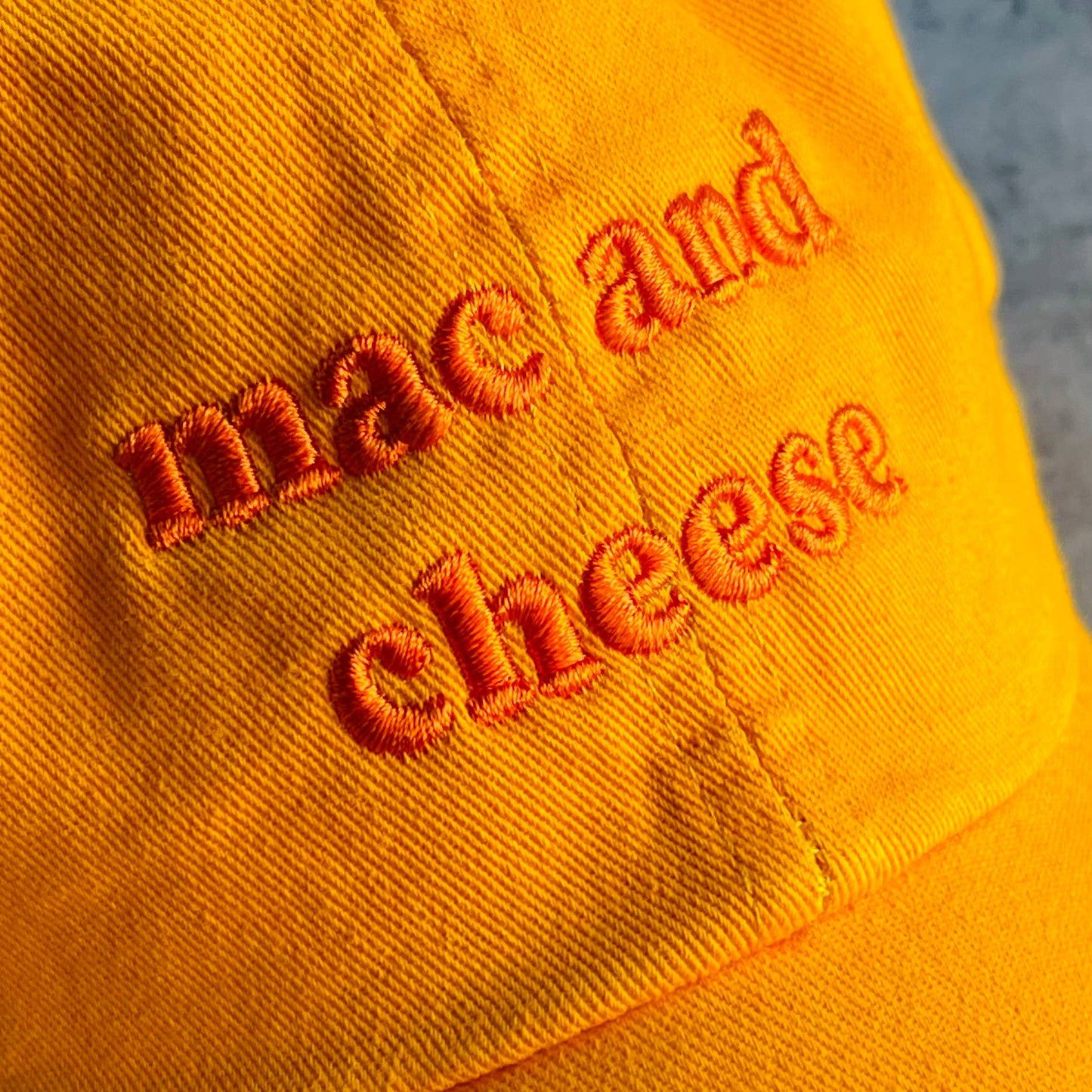 Orange hat with orange embroidery that reads: mac and cheese