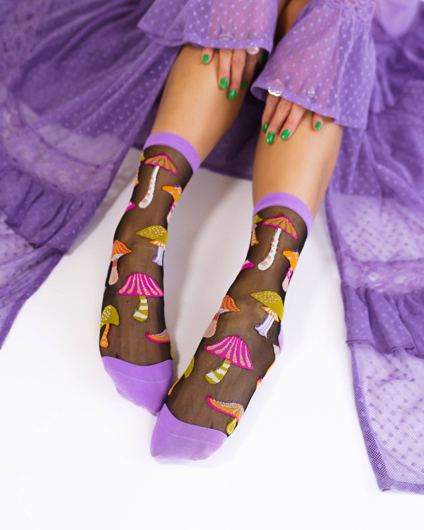 Sheer socks with mushroom pattern worn by a person in a purple outfit.