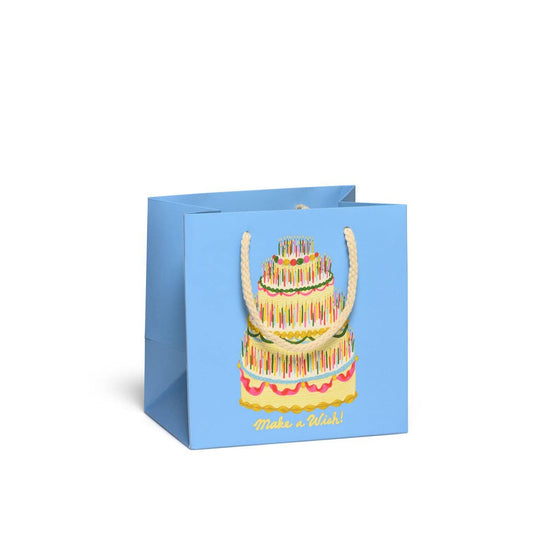 Gift bag in robin egg blue with image of four-tiered, frosted cake with dozens of candles on each tier. Metallic gold text on the bottom reads "Make a Wish"