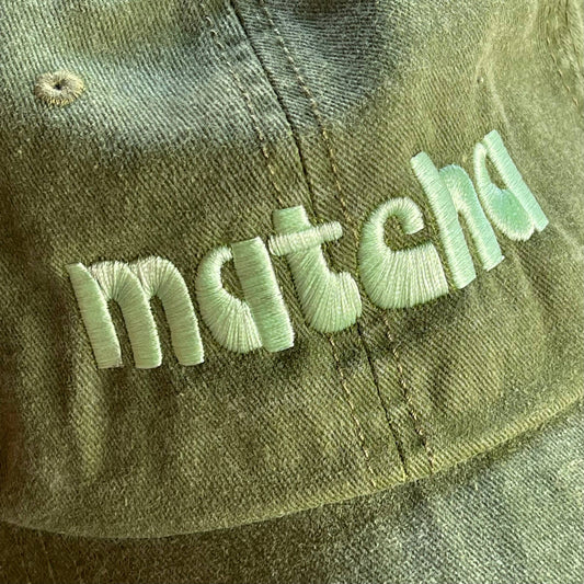 Faded olive green baseball hat with light green "matcha" embroidered in a retro font. Shown from different angles.