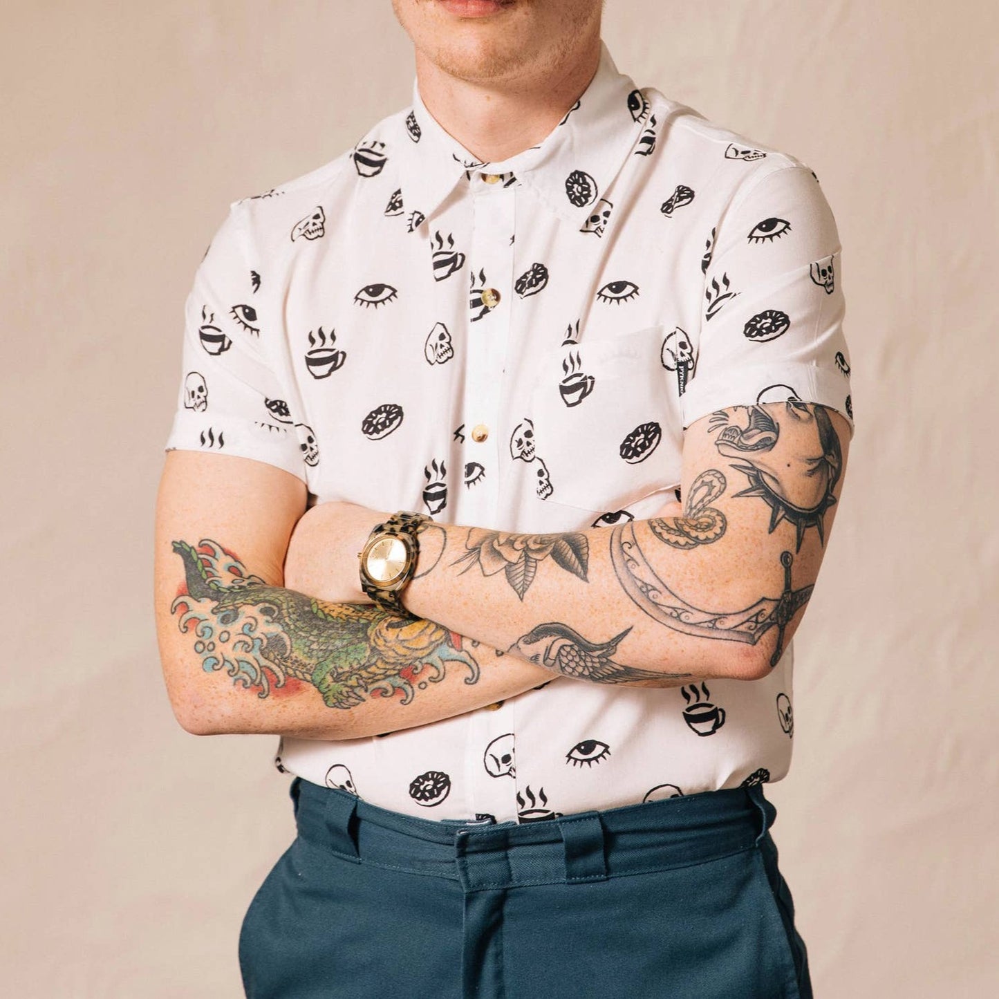 White button up shirt with tortoise buttons. Patterned with skulls, donuts, coffee and eyes.