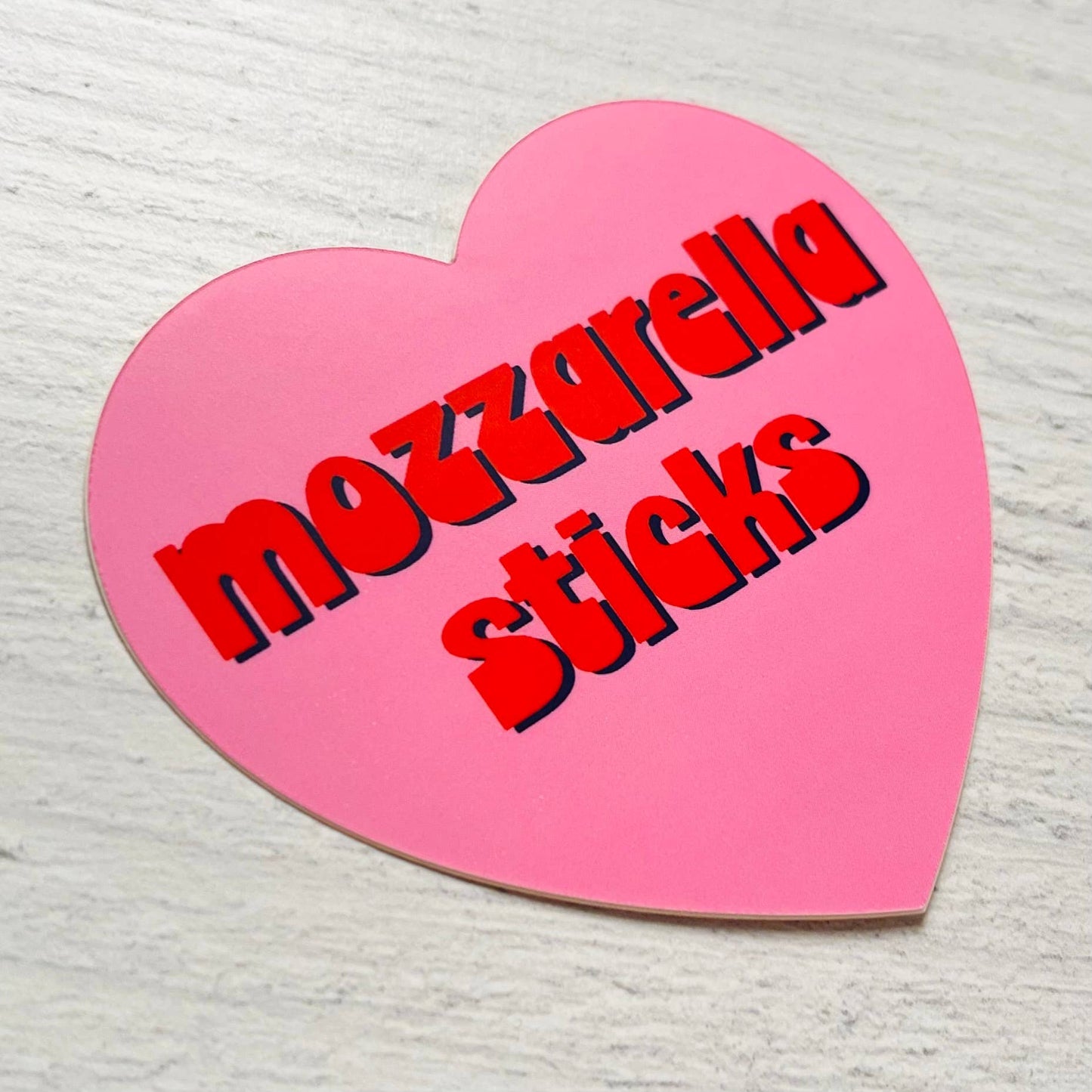 Heart shaped pink sticker with "mozzarella sticks" text in red retro font.