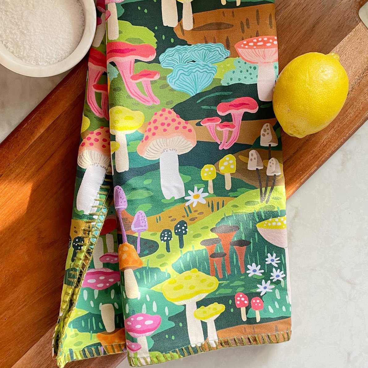 Colorful mushroom tea towel. Shown here on cutting board with a lemon and bowl of salt