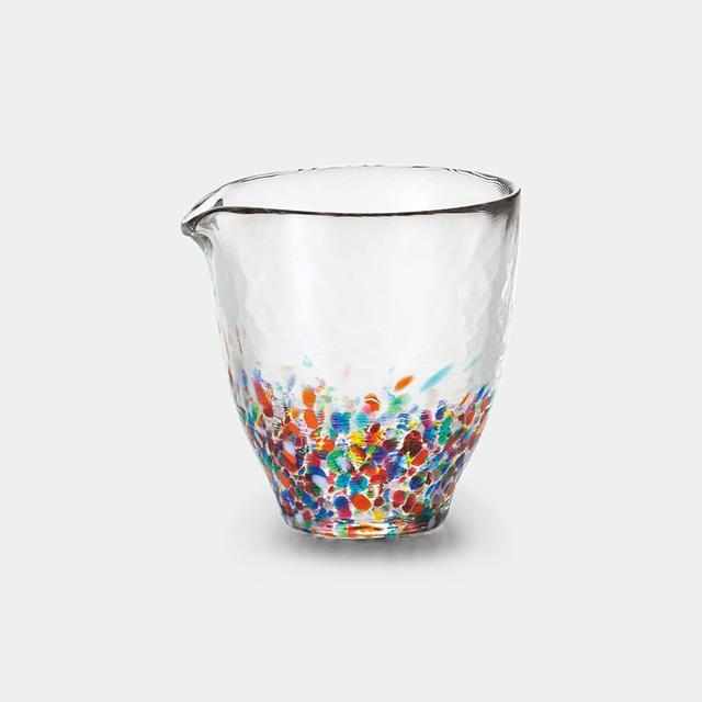 Clear glass pitcher with multicolored speckles on a white background