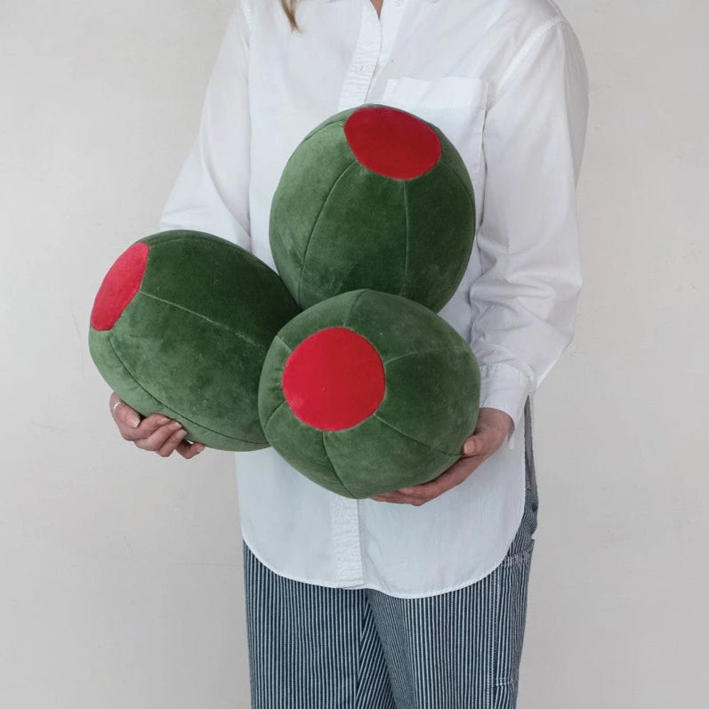 Person holding three green olive pillows