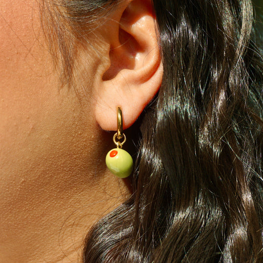 Close-up of an ear wearing a green bead olive with a small red detail.