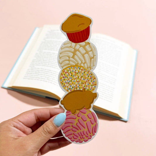 Colorful sweet mexican pastries bookmark held by a hand with a pink background