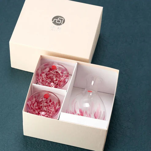 Set of sake glassware with red speckled design in a light pink box on a blue background