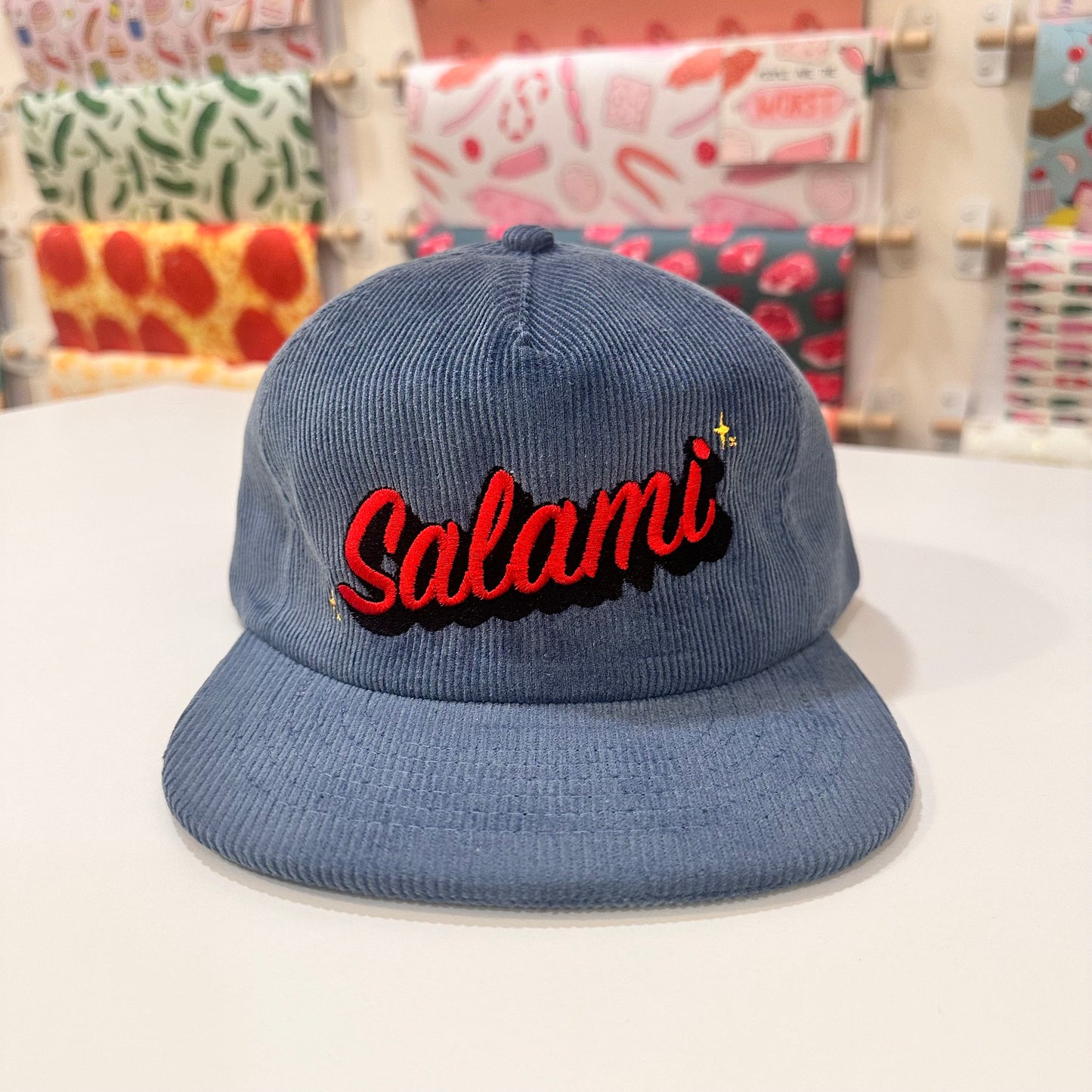 Light Blue corduroy hat that has Salami embroidered on the front in red with yellow starbursts.