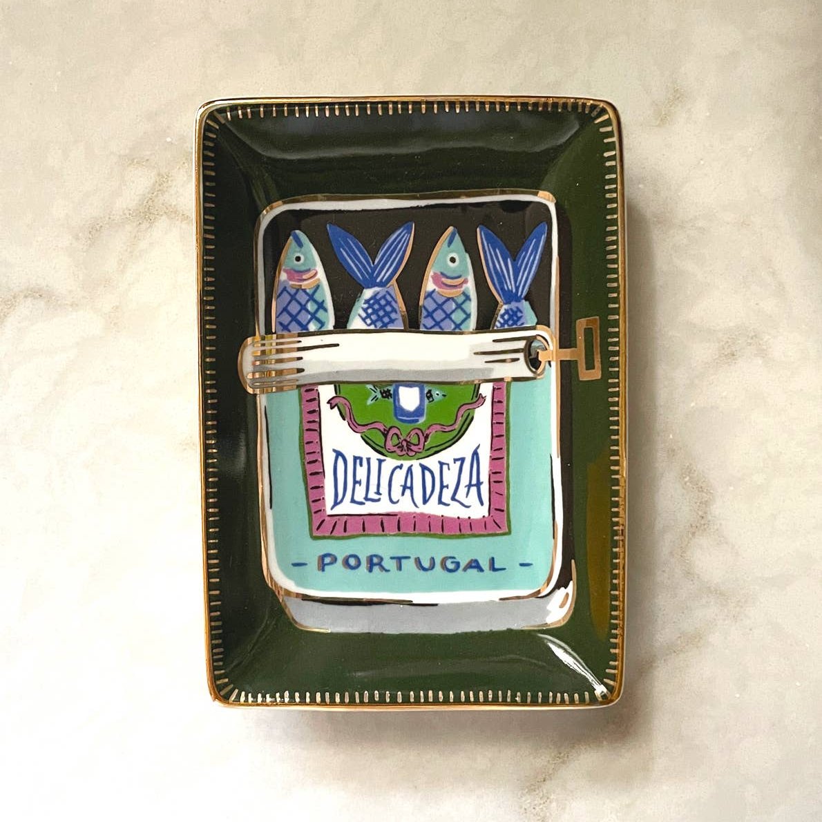Sardine trinket tray -- olive green border with illustration of an open tinned can of sardines. Text on tin reads "delicadeza portugal"
