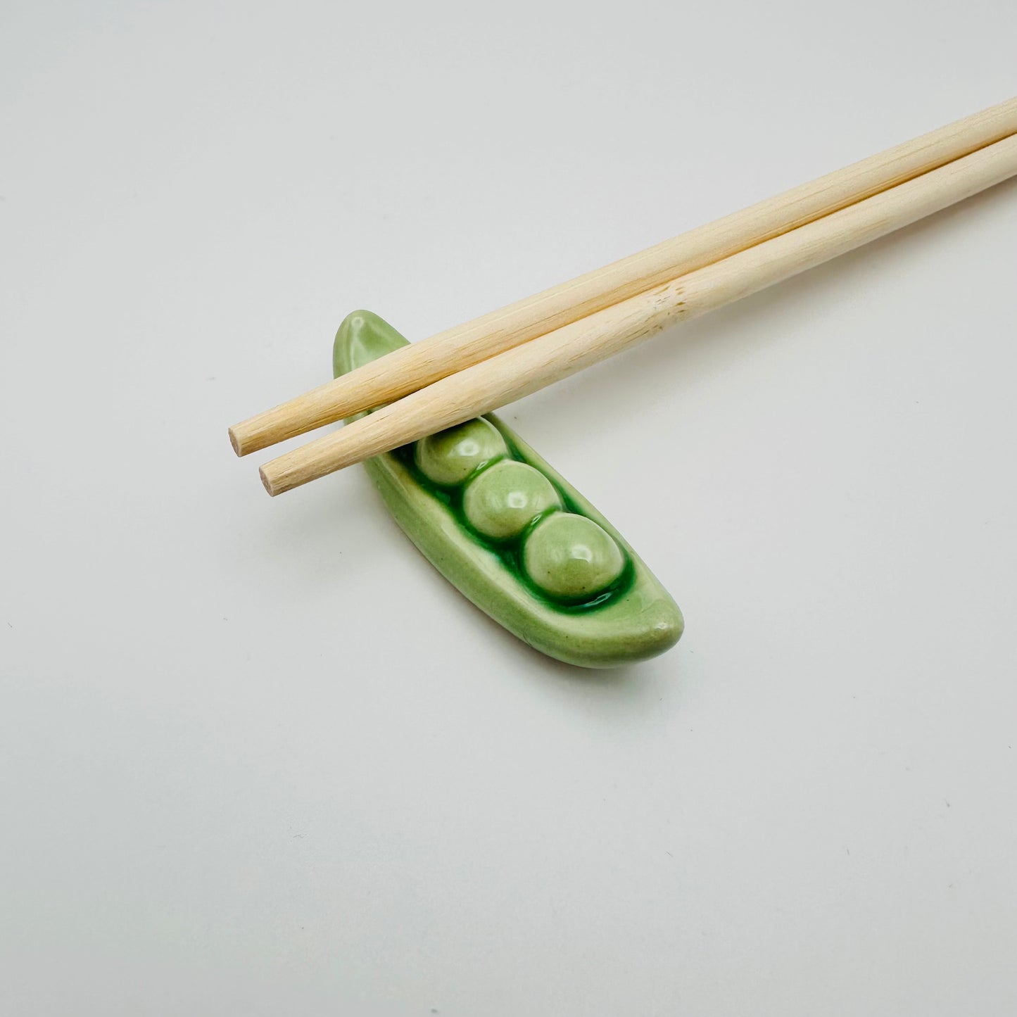 Snap Pea Chopstick Rest with a pair of chopsticks resting on them.
