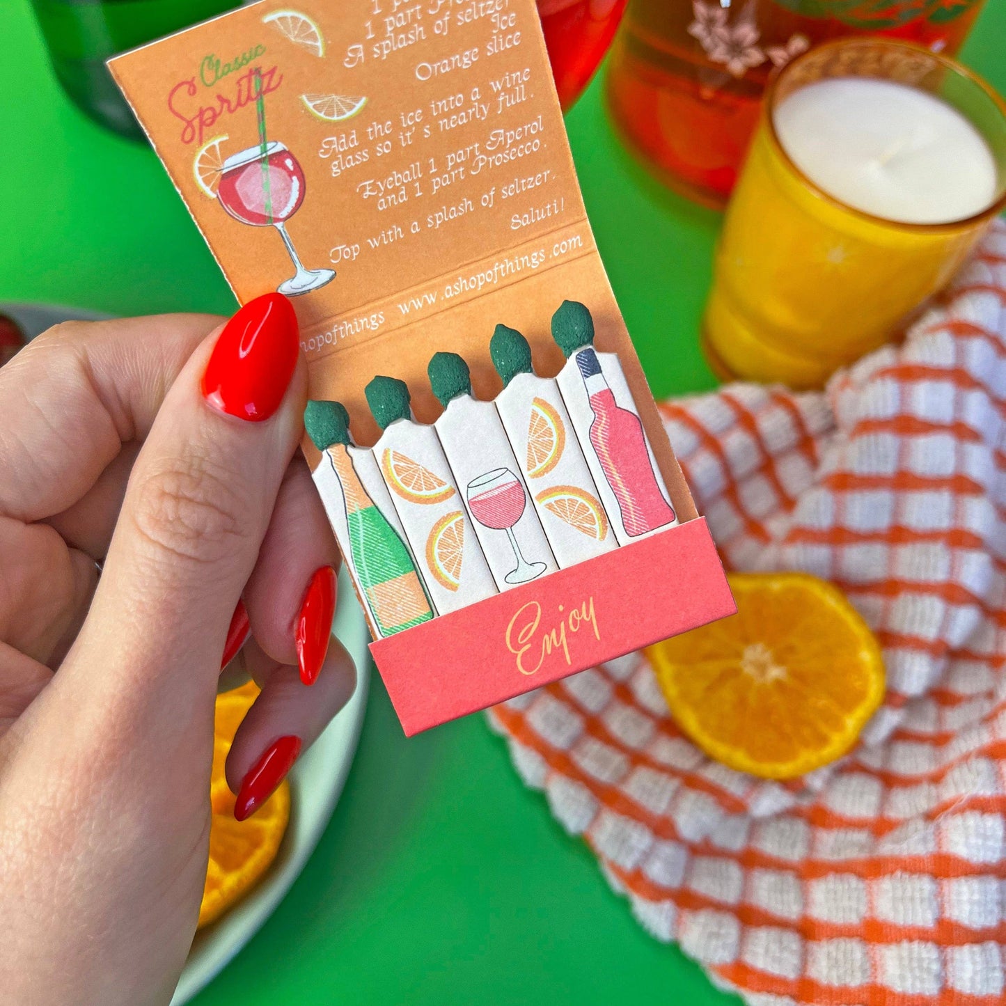 Negroni matchbook. Each match has a different ingredient on each match. Inside the matchbook is a recipe of how to make a spritz. The matchbook says Enjoy