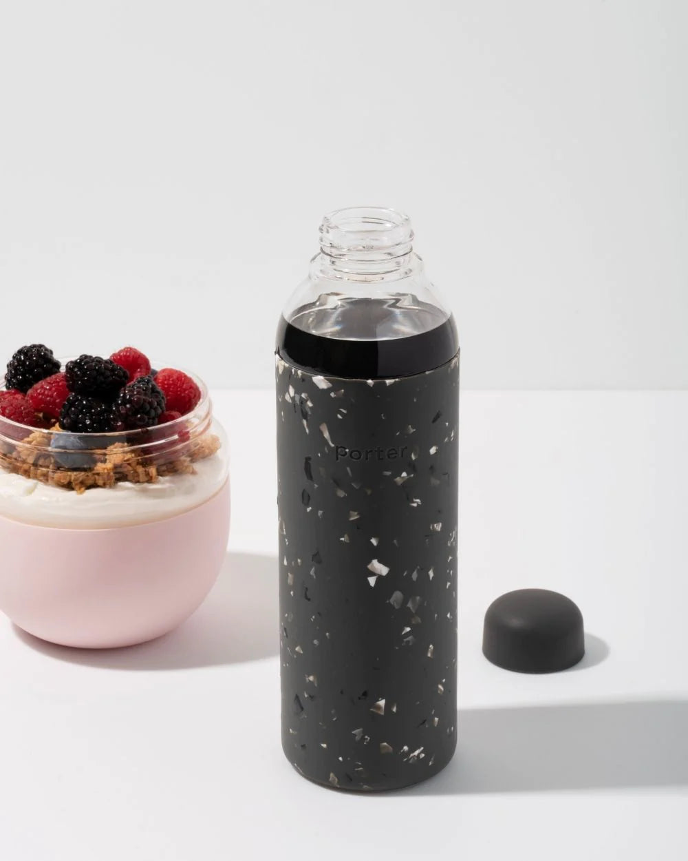 Glass reusable water bottle with terrazzo print silicone wrapped around for design and grip