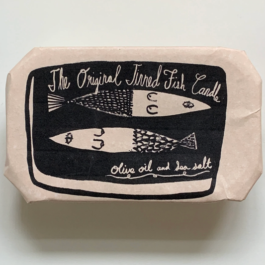 Tinned Fish Candle outer paper packaging -- text up top reads "The Original Tinned Fish Candle", two fishes in the center and underneath text reads "olive oil and sea salt"